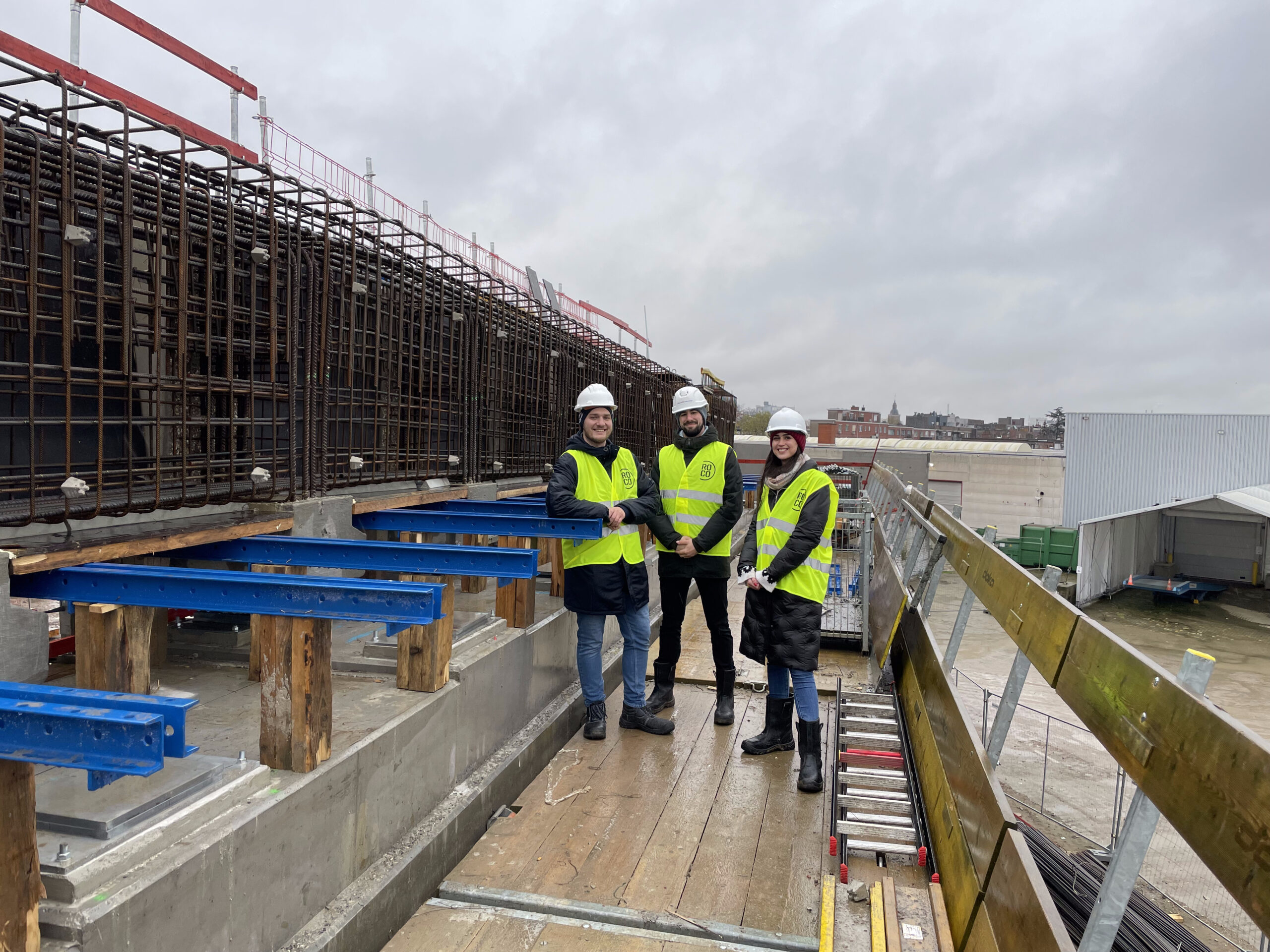 Rebar detailers and a project manager discussing reinforcement drawings at a construction site.